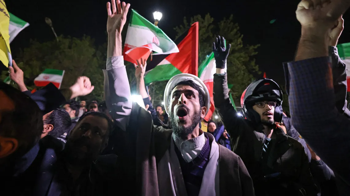 Demonstranci z irańskimi i palestyńskimi flagami w noc irańskiego ataku zebrali się pod brytyjską ambasadą w Teheranie. Teheran, 14 kwietnia 2024 r. / fot. ATTA KENARE/AFP/East News